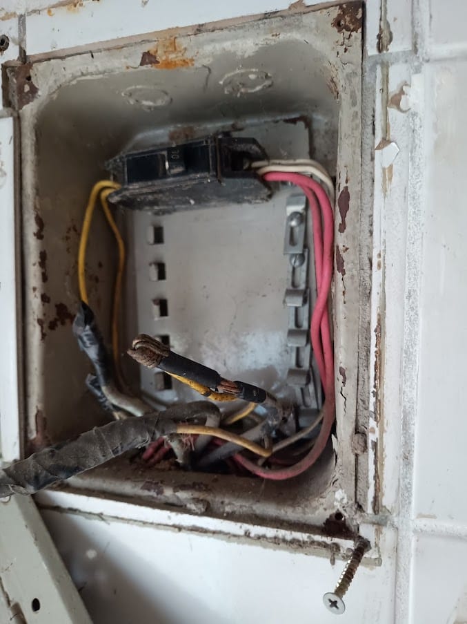Quadro elétrico antigo com caixa corroída e fiação exposta
