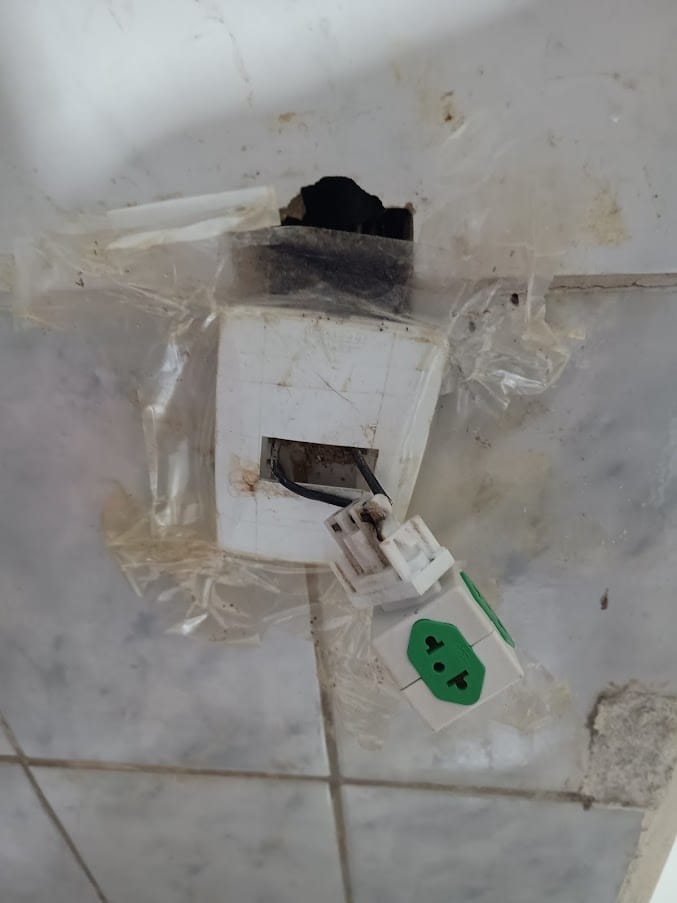 Tomada danificada e queimada na parede