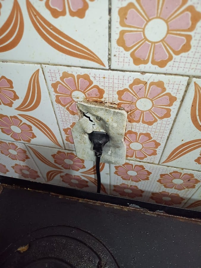 Tomada queimada em parede revestida de azulejo